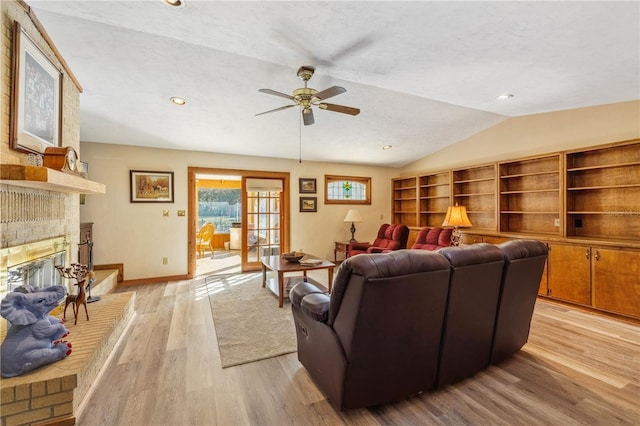 living room featuring a fireplace, light hardwood / wood-style flooring, vaulted ceiling, a textured ceiling, and ceiling fan