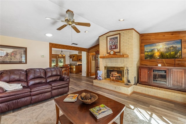 living room featuring ceiling fan, wood-type flooring, a fireplace, and vaulted ceiling