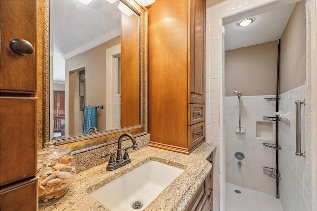 bathroom with a tile shower, ornamental molding, and vanity