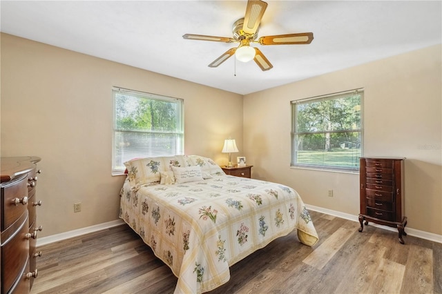 bedroom with multiple windows, hardwood / wood-style flooring, and ceiling fan