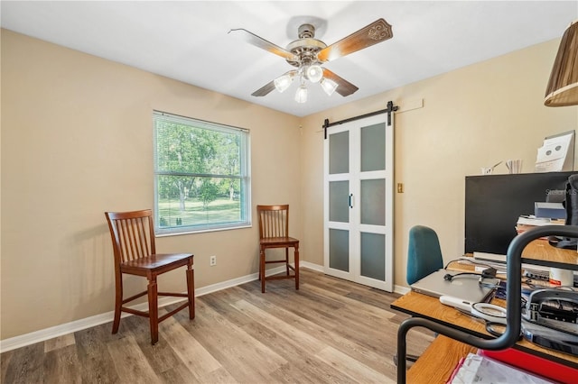 office space featuring light hardwood / wood-style flooring, a barn door, and ceiling fan