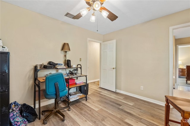 office with light wood-type flooring and ceiling fan