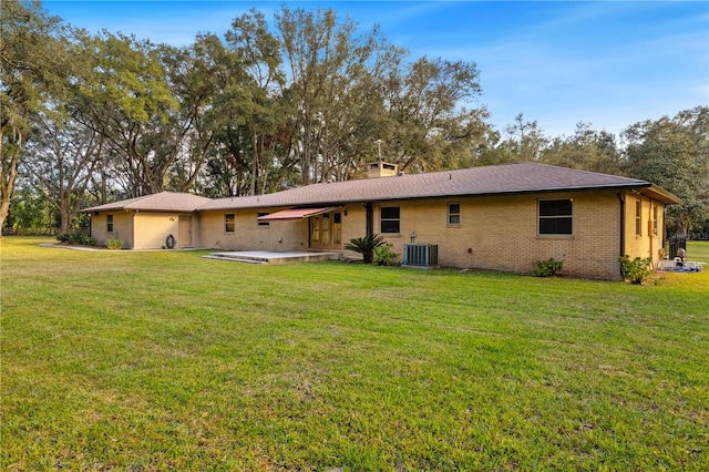 rear view of house featuring a patio, a lawn, and central AC unit