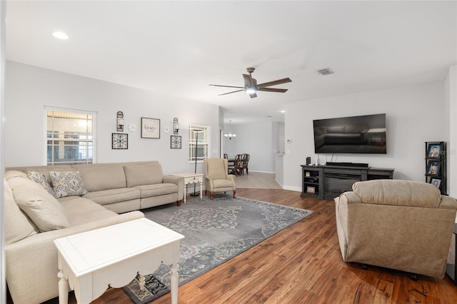 living room with ceiling fan with notable chandelier and dark hardwood / wood-style flooring