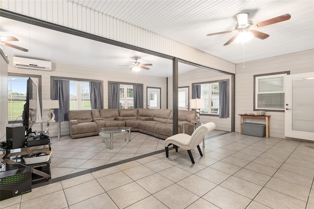 tiled living room featuring a wall unit AC, ceiling fan, and a wealth of natural light