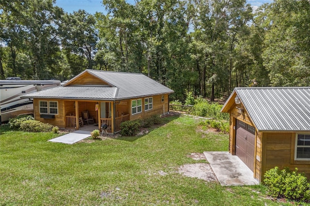 exterior space with a garage, a yard, an outbuilding, and covered porch