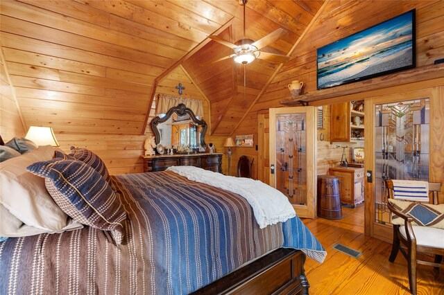 bedroom with wooden walls, light hardwood / wood-style floors, wooden ceiling, and vaulted ceiling