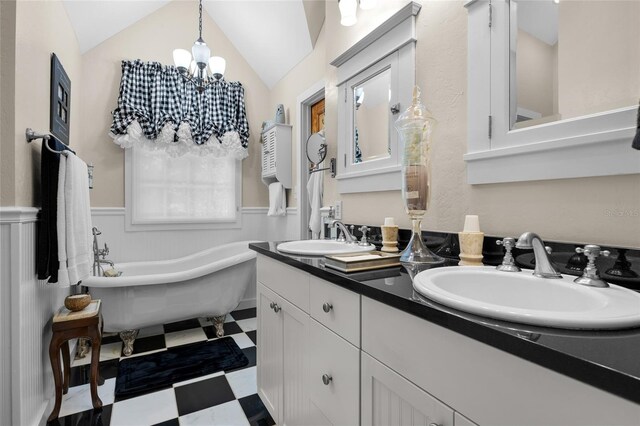 bathroom with vanity, a bath, vaulted ceiling, and an inviting chandelier