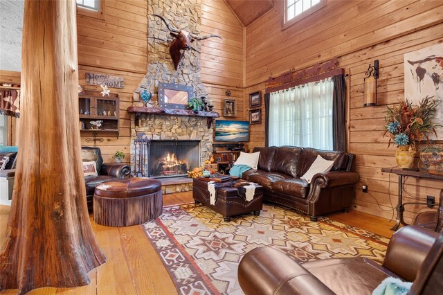 living room with a fireplace, a towering ceiling, wood-type flooring, and wood walls