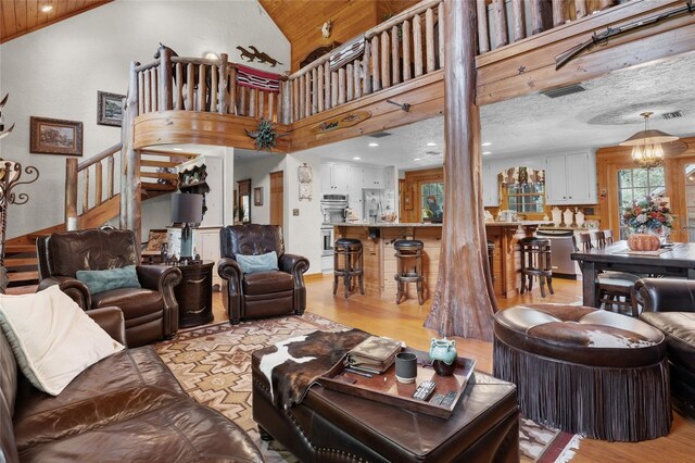 living room featuring high vaulted ceiling, a chandelier, light hardwood / wood-style floors, and wooden ceiling