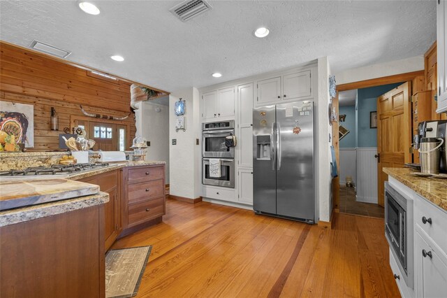 kitchen featuring stainless steel appliances, white cabinetry, and light hardwood / wood-style floors