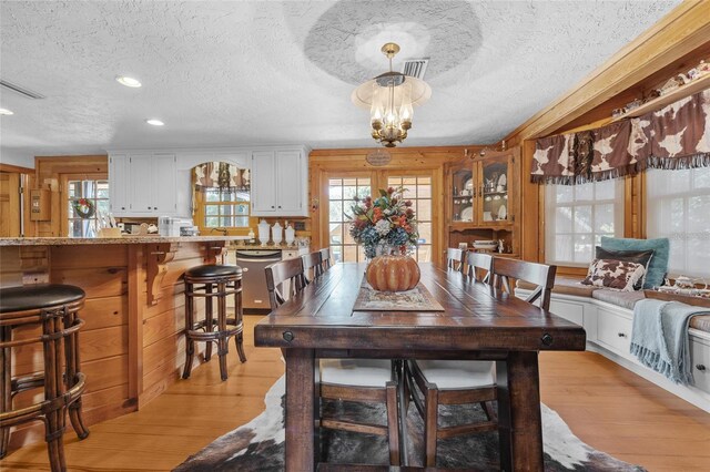 dining room with a notable chandelier, light hardwood / wood-style floors, a textured ceiling, and a wealth of natural light