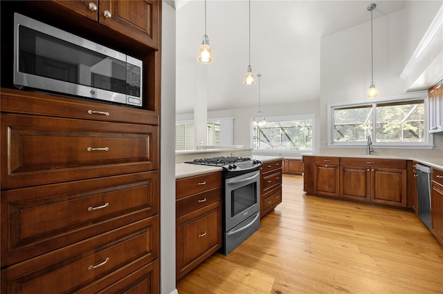 kitchen featuring appliances with stainless steel finishes, light countertops, light wood-style floors, and a sink