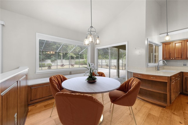 dining area featuring high vaulted ceiling and light wood finished floors