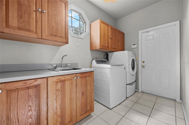 washroom with light tile patterned floors, separate washer and dryer, a sink, and cabinet space