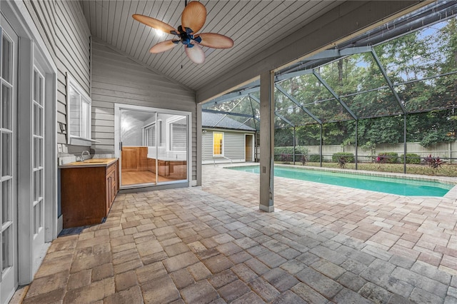 view of swimming pool with a fenced in pool, glass enclosure, a fenced backyard, ceiling fan, and a patio area