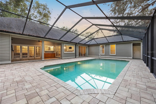 pool at dusk featuring a patio, a lanai, a ceiling fan, and an outdoor pool