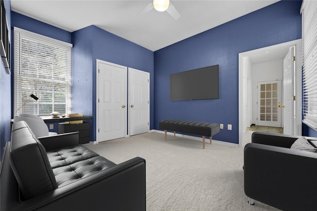 carpeted living area featuring a ceiling fan and baseboards