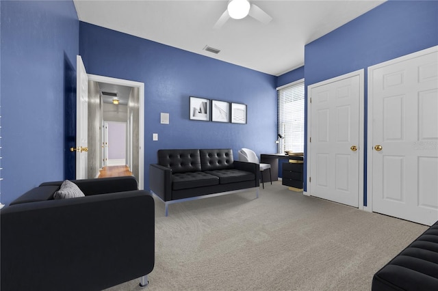 living room featuring carpet floors, ceiling fan, and visible vents