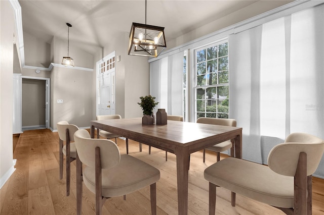 dining space featuring lofted ceiling, light wood-type flooring, a chandelier, and baseboards