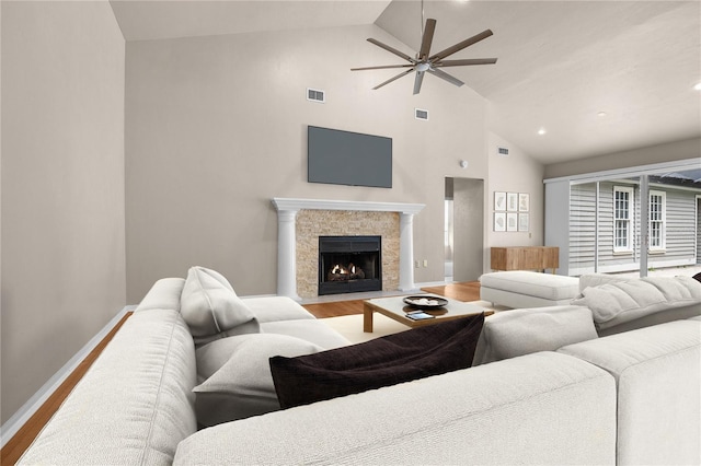 living area featuring a fireplace with flush hearth, visible vents, baseboards, and wood finished floors