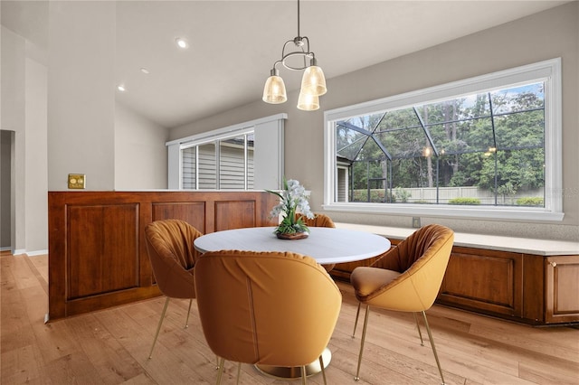 dining area with light wood-type flooring, plenty of natural light, a notable chandelier, and lofted ceiling