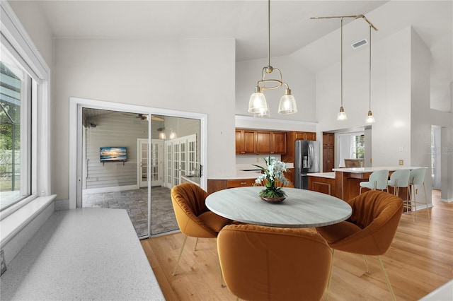 dining space featuring high vaulted ceiling, visible vents, and light wood finished floors