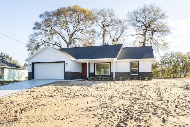 ranch-style house with an attached garage, stone siding, concrete driveway, and stucco siding