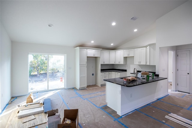 kitchen with dark countertops, visible vents, white cabinets, a sink, and a peninsula