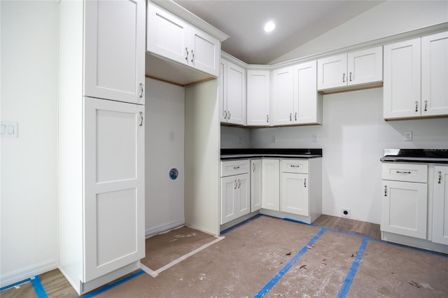 kitchen featuring vaulted ceiling, dark countertops, white cabinetry, and recessed lighting