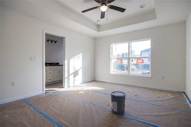 spare room featuring baseboards, a tray ceiling, and ceiling fan