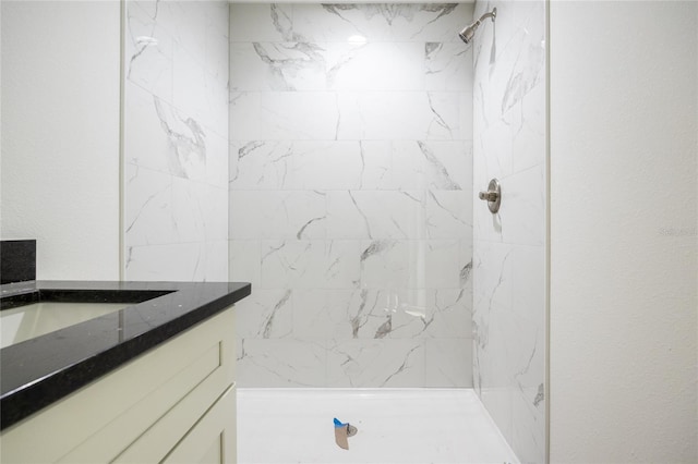 bathroom with tiled shower and vanity