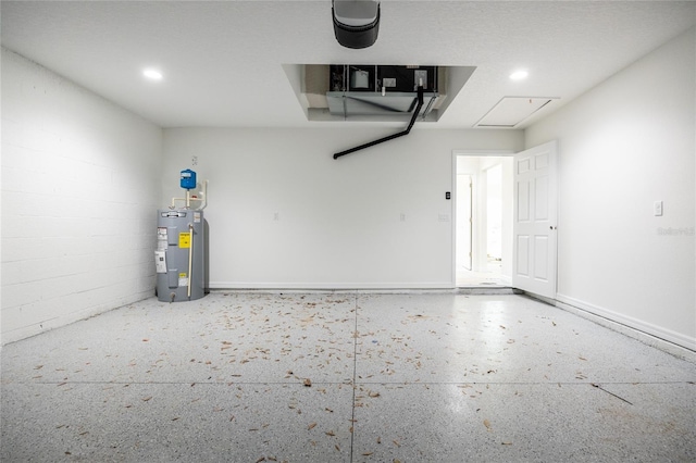 garage featuring concrete block wall, electric water heater, and recessed lighting