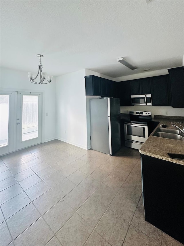 kitchen featuring an inviting chandelier, a textured ceiling, sink, appliances with stainless steel finishes, and decorative light fixtures