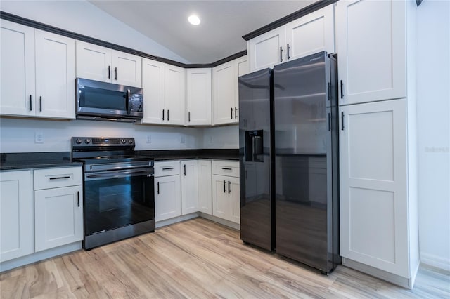 kitchen with appliances with stainless steel finishes, light hardwood / wood-style flooring, white cabinetry, and lofted ceiling