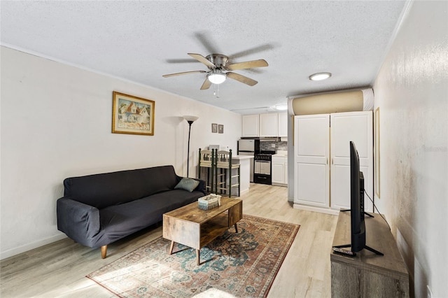 living room with light hardwood / wood-style floors, ceiling fan, a textured ceiling, and ornamental molding