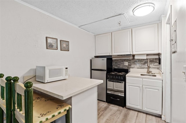 kitchen featuring white cabinets, sink, gas stove, stainless steel refrigerator, and light hardwood / wood-style flooring