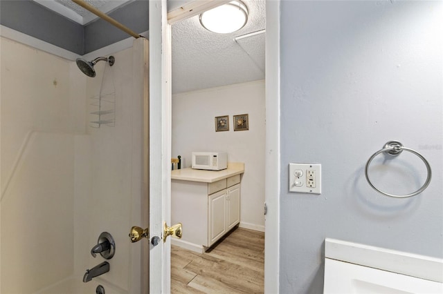 bathroom with vanity, hardwood / wood-style flooring, shower / washtub combination, and a textured ceiling