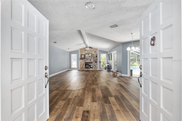 entryway with dark wood-type flooring, ceiling fan with notable chandelier, vaulted ceiling with beams, and a fireplace