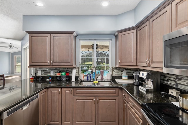 kitchen with appliances with stainless steel finishes, dark stone counters, sink, and backsplash