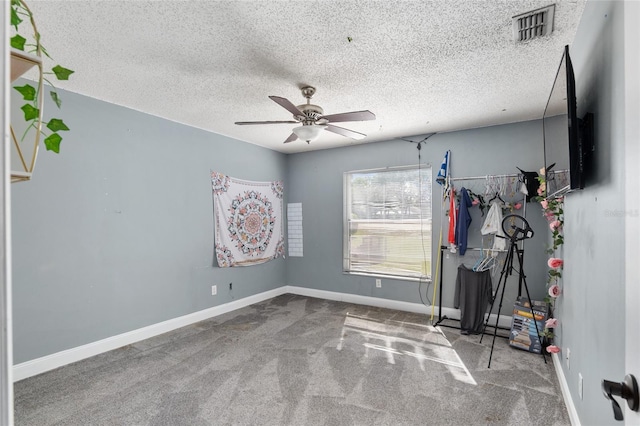 interior space with ceiling fan, a textured ceiling, and carpet