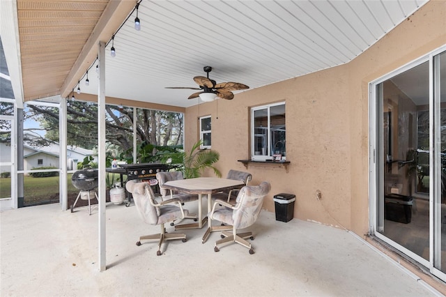 view of patio featuring ceiling fan and glass enclosure