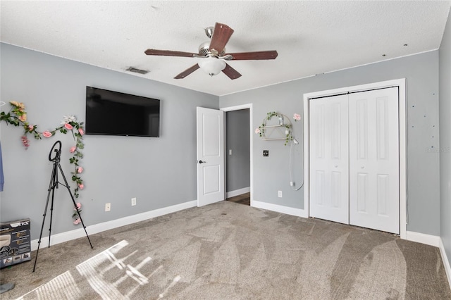 unfurnished bedroom with ceiling fan, a textured ceiling, carpet flooring, and a closet