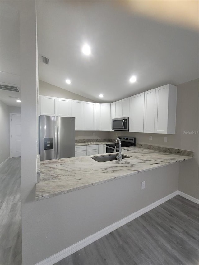 kitchen with visible vents, light stone counters, stainless steel appliances, white cabinetry, and a sink