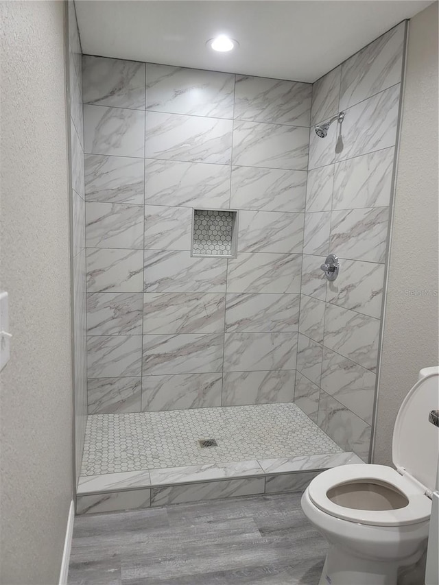 bathroom featuring recessed lighting, a stall shower, toilet, and a textured wall