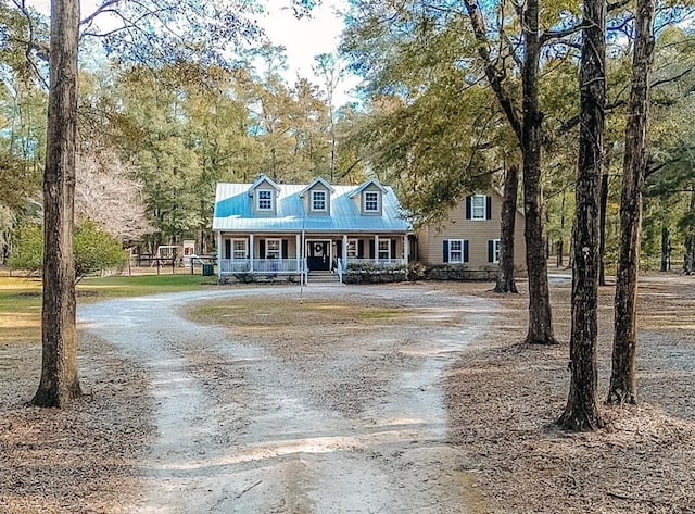 cape cod home with a porch and dirt driveway