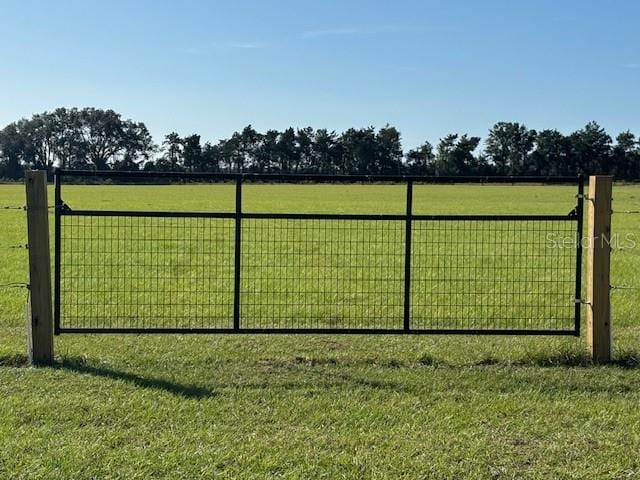 view of gate featuring a lawn and a rural view