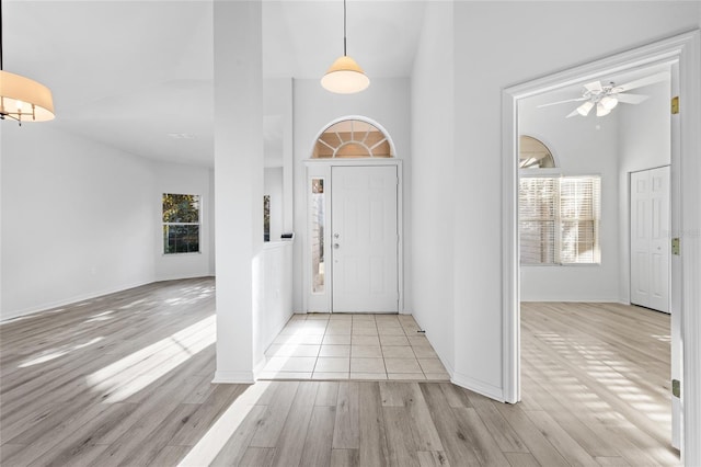 entryway with a healthy amount of sunlight, light hardwood / wood-style floors, and a high ceiling