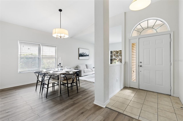 foyer entrance featuring light wood-type flooring, baseboards, and vaulted ceiling