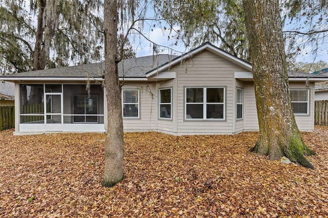 rear view of house with fence and a sunroom